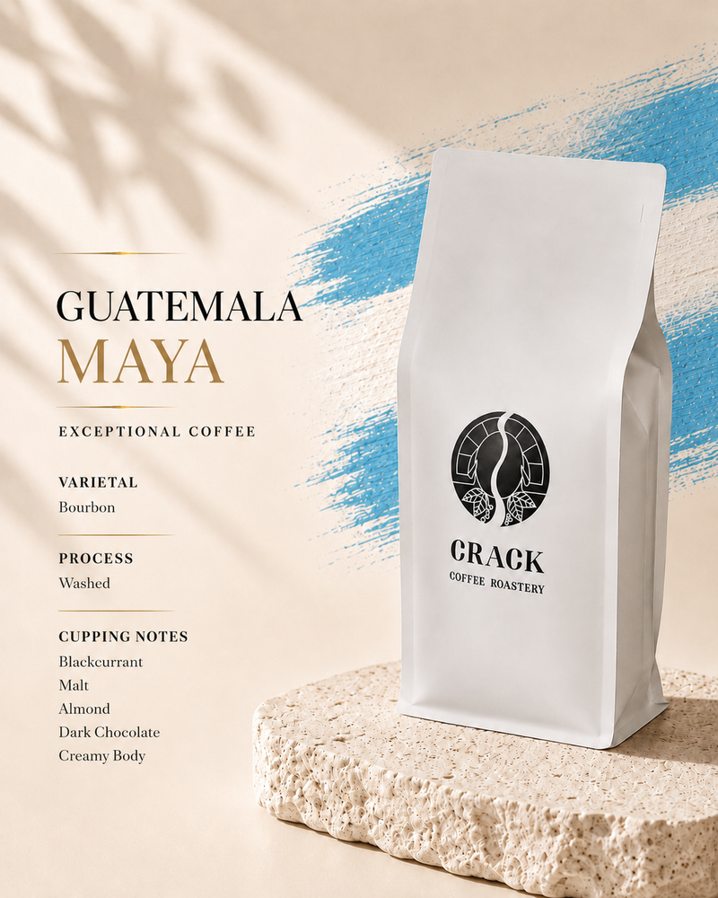 A white stand-up coffee bag labeled CRACK COFFEE ROASTERY stands on a textured stone slab against a warm beige background with blue brushstroke accents and shadow overlays. Text on the left reads GUATEMALA MAYA with coffee variety and cupping notes.