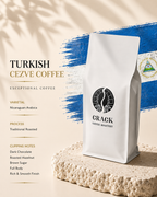 A white bag of Crack Coffee Roastery Turkish Cezve Coffee stands on a textured stone slab against a beige background with a blue brushstroke graphic and text describing the coffee variety, roast, and flavor notes.